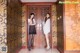 A couple of women standing in front of a wooden door.