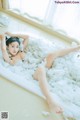 A woman laying in a bathtub covered in foam.