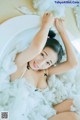 A woman laying in a bathtub covered in fluffy white cotton.