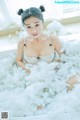 A woman sitting in a bathtub covered in foam.