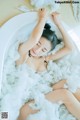 A woman laying in a bathtub covered in foam.