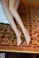 A close up of a woman's legs wearing high heels on a rug.