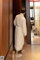 A man in a bathrobe standing in front of a door.