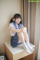 A young woman in a school uniform sitting on a desk.