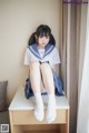 A woman in a school uniform sitting on a table.