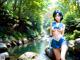 A woman in a blue and white outfit standing on a rock by a river.