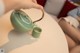 A person pouring tea into a green teapot on a table.