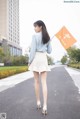 A woman walking down a street holding an orange flag.