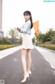 A woman in a skirt and high heels holding an orange flag.