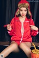 A woman in a red jacket and hat sitting on a table.