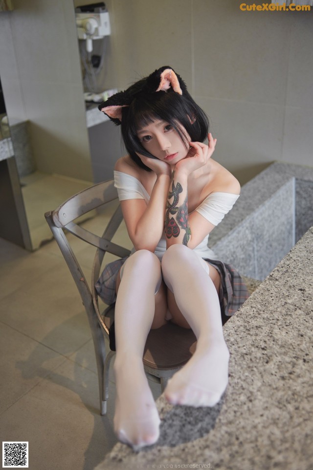 A woman sitting on a chair in a bathroom.