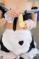 A woman in a maid outfit holding a banana.