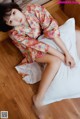 A woman in a kimono sitting on a bed.