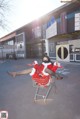 A woman in a santa suit sitting in a shopping cart.