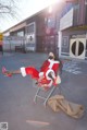 A woman in a santa suit sitting in a shopping cart.