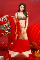 A woman in lingerie posing next to a red lion.