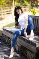 A woman sitting on a wooden bench in a park.