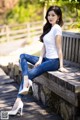 A woman sitting on a wooden bench wearing high heels.