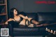 A woman laying on a black couch in lingerie.