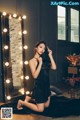 A woman in a black dress sitting on the floor in front of a mirror.