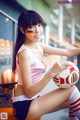 A woman sitting on a bench holding a soccer ball.