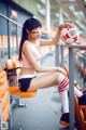 A woman sitting on a bench holding a soccer ball.