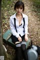 A woman in a school uniform sitting on a bench.