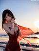 A woman in a red dress standing on a beach.