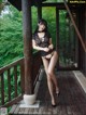 A woman in a black lingerie posing on a porch.