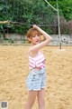 A young woman standing in front of a volleyball net.