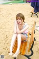 A woman sitting on a wooden bench on the beach.