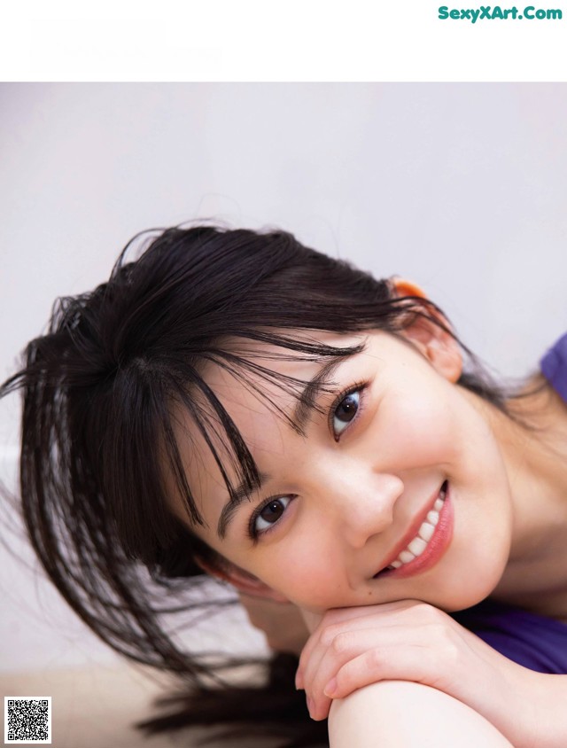 A young woman laying on the floor with her hand on her chin.