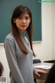 A woman standing in front of a blackboard in a classroom.