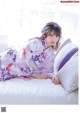 A woman in a kimono laying on a bed.