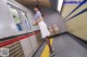 A woman in a white dress is standing on a subway platform.