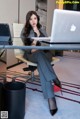 A woman sitting at a desk with a laptop computer.